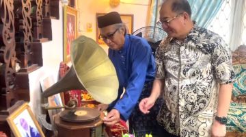 Cikgu Serbini (kiri) menunjuk kepada Pang cara memainkan gramofon.