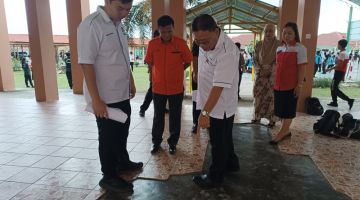 Chiew (kiri) bersama Penolong Kanan Hal Ehwal Murid (HEM) SMK Pujut Tai Chu Ping (tiga kiri) meninjau keadaan lantai bangunan sekolah itu yang sudah pecah. 