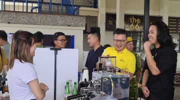 Chieng melawat salah satu gerai menjual minuman kopi sambil disaksikan Chris (kanan) pada Program Microwave di SMK Methodist, hari ini.