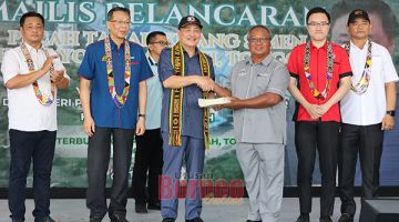 SERAH: Hajiji menyampaikan geran hak milik tanah kepada wakil salah sebuah kampung di Tongod.