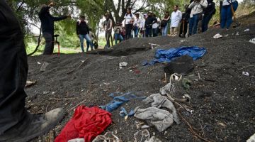 Orang ramai berdiri sekitar cebisan pakaian di tapak yang kelihatan seperti kubur besar yang ditemui di tenggara Kota Mexico kelmarin. — Gambar AFP