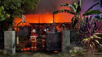 Anggota bomba berusaha memadamkan salah satu rumah yang terbakar di Jalan Patinggi Ali, awal pagi tadi. - Gambar JBPM Sarawak
