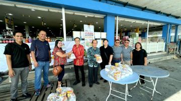 Wong (enam kanan) menyerahkan set barangan makanan asas kepada salah seorang pembeli di Sibu Jaya, semalam.