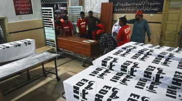 Sukarelawan memindahkan keranda pekerja pendatang yang maut ditembak ke rumah pengebumian Edhi Foundation di Karachi kelmarin. — Gambar AFP 