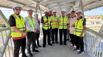 Lee bersama wakil JKR dan pihak kontraktor meninjau perkembangan terkini projek jejantas pejalan kaki berhadapan SK Tudan, hari ini.