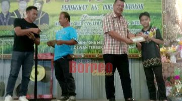 SAMPAIKAN: Danil menyampaikan hadiah kemenangan kepada pemenang dalam Pertandingan Paluan Gong sempena sambutan Pesta Kaamatan Kampung Pogun Antolob Bingkor.