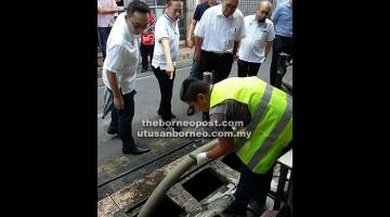 SAKSI: Adam (tengah) menyaksikan demonstrasi menyedut sampah dari parit dilakukan di Pasar Pusat Miri semalam. 