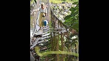USANG: Salah seorang penduduk Kampung Napong 1 meniti jambatan gantung yang sudah usang.