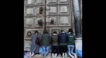 TAAT: Penziarah dilihat berdoa di depan pintu Gereja Holy                     Sepulchre di Kota Lama Baitulmuqqadis kelmarin. — Gambar AFP
