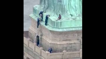 AKSI BERANI: Gambar pegun diambil daripada video serahan saluran berita PIX11 News             di New York menunjukkan anggota polis bercakap dengan seorang wanita selepas dia mendaki ‘Statue of Liberty’ di New York kelmarin. — Gambar AFP