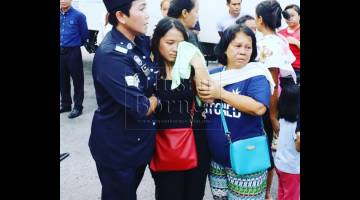 Natasha (tengah) ditenangkan oleh ibu serta anggota polis semasa tiba di Terminal MasCargo, hari ini