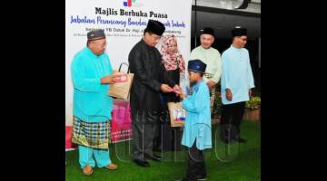 JAUJAN (dua kiri) menyampaikan sumbangan kepada anak yatim yang diraikan sempena Majlis Berbuka Puasa anjuran Jabatan Perancangan Bandar dan Wilayah Sabah pada Isnin. Turut kelihatan Mursidi (kiri) dan Masnah (tengah).