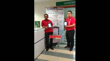 PROMOSI: Justyn (kanan) dan Francis menunjukkan e-paper See Hua Marketing yang sedang dalam rangka promosi di Normah semalam.