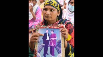 KORBAN: Paramjit Kaur menunjukkan gambar suaminya Joga Singh yang merupakan salah seorang mangsa todi beracun di kampung Muchhal, 30km dari Amritsar, kelmarin. — Gambar AFP