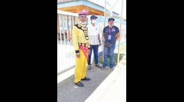 BAJU TRADISI: Akiah bergambar bersama petugas pilihan raya di SK Tamau.