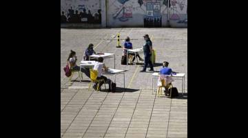 KEMBALI BERSEKOLAH: Sekumpulan pelajar tahun akhir sedang mengikuti kelas di pekarangan sekolah di Buenos Aires kelmarin. — Gambar AFP