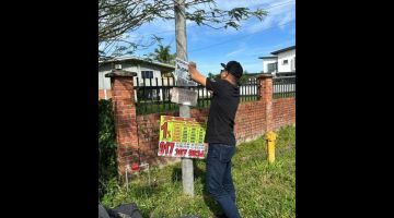 OPS VULTURE: Pasukan polis menurunkan salah satu poster semasa Ops Vulture sekitar sini.