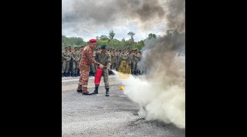 Mosihi (kiri) membantu anggota 13 RAMD Kem Pakit mengendalikan alat pemadam api semasa menyertai sesi latihan.
