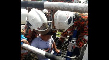 Anggota bomba memotong besi jeriji penutup longkang untuk mengeluarkan kaki kanan seorang murid yang tersepit dalam kejadian di Kampung Baru, Bintulu hari ini.